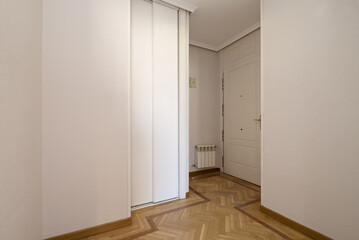 view of the hall of a house with a white wooden door, a built-in wardrobe