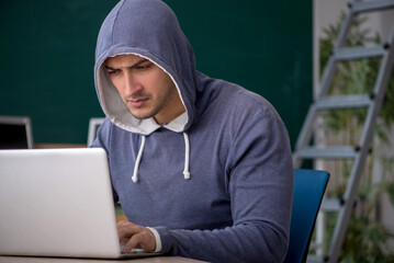 Young male hacker sitting in the classroom