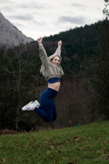 Blissful Mountain Bound: A Joyful Blonde Woman Leaping in Nature's Serene Wilderness
