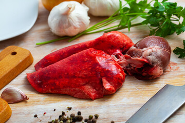 Fresh mutton offals, lungs and heart, on wooden background with parsley, garlic and onion