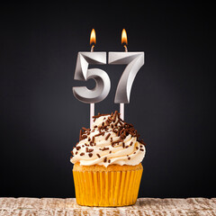 birthday cupcake with number 57 candle - Celebration on dark background
