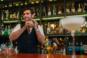 Professional Caucasian man bartender preparing and serving cocktail drink to customer on bar counter at nightclub. Barman making mixed alcoholic drink for celebrating holiday party at restaurant bar.