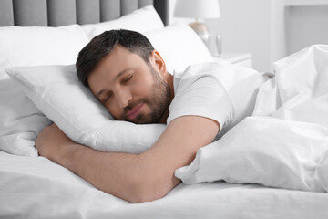 Fototapeta na wymiar Handsome man sleeping in soft bed at home