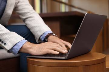 Man using modern laptop at table in cafe, closeup