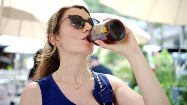 Woman drinking kombucha at a terrace, slow motion
