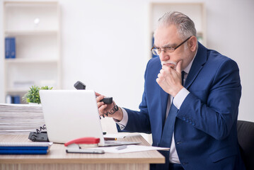 Fototapeta premium Old male employee working in the office