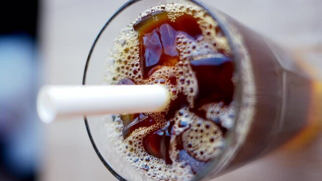 Cold brew coffee and bubble tea in a glass with ice and big white straw close up slow motion, vertical screen