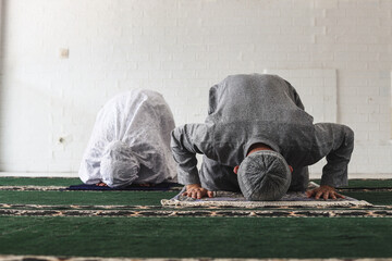Front view of religious muslim couple praying together at home doing sujud movement called a Sajdah...