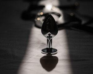 Anal plug and leather mask on white sheet. 