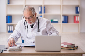 Old male doctor working in the clinic