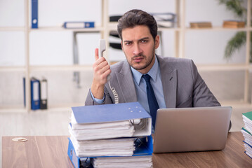 Naklejka premium Young male employee and too much work in the office