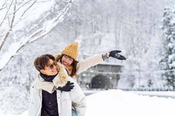 Happy Asian couple have fun playing snow ball during travel small town and forest mountain together...