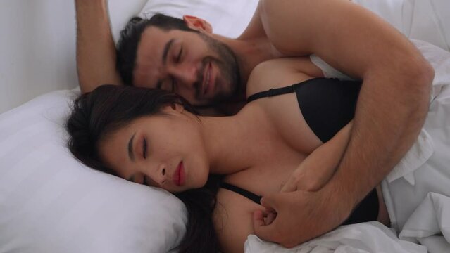 Caucasian young man and woman starting foreplay and making love on bed.