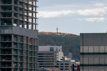 vue sur une tour en construction en béton avec vue sur une colline avec une croix au sommet en été