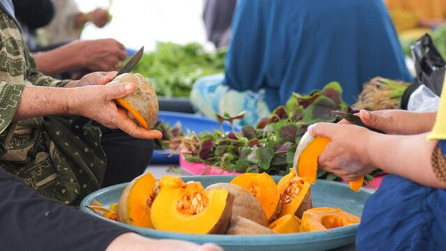 An elderly Indonesian woman's hands cut a pumpkin during a communal cooking event in Tarakan, Indonesia