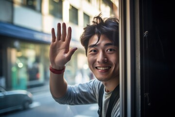 a photo portrait of a young happy smiling handsome guy waving with his hand out of the window and saying goodbye on a sunny day. Generative AI - Powered by Adobe