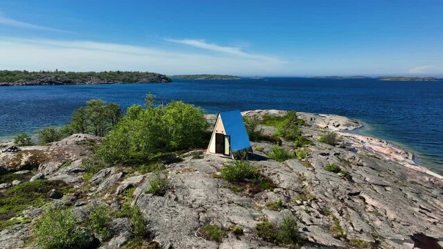 Aerial view away from a self-sufficient cabin on a rocky island, in sunny Finland