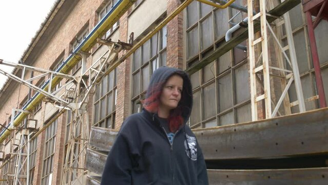 Mysterious Girl in a hoodie walking through an industrial place. Medium shot slow motion.