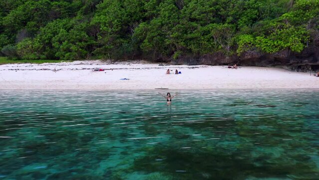 Female Tourist Swimming On The Pristine Water Of Gunung Payung Beach In Bali, Indonesia. Zoom In