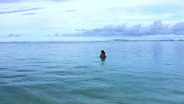A Woman In A Crystal Clear Water Of Gunung Payung Beach In Bali Indonesia. Aerial Pullback Shot