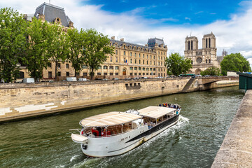 River cruise boat and Notre Dame de Paris in a summer day, France