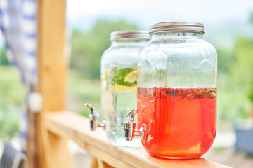 Glass bank of lemonade with sliced citrus fruits on a buffet table. Summer party outdoor. Detox.