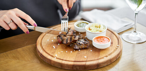 Lunch in a restaurant, a woman eats Pieces of liver cooked on the grill. Serving on a wooden Board. Barbecue restaurant menu, a series of photos of different meats.