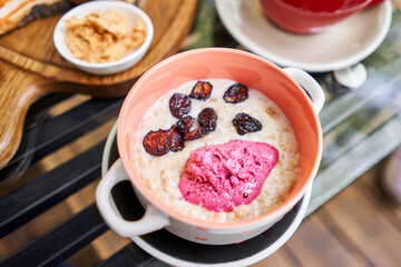 Breakfast with fresh cooked porridge served with Dry Cherry with strawberry sorbet in bowl. Assorted sliced bread on a wooden board. Served with smoked butter. Breakfast with cappuccino coffee.
