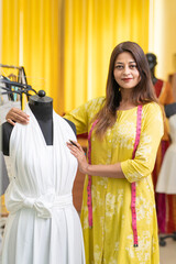 Young indian female fashion designer standing at store