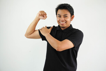 young asian man against a vibrant white studio background, showing strength gesture with arms, symbol of power wearing black polo t shirt.