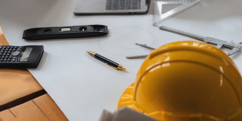 Engineer workplace with blueprint, compass, pen, construction level and safety helmet