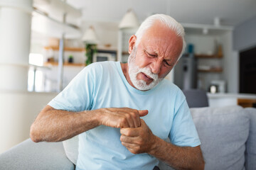 Elderly man has pain in fingers and hands. Old man with finger pain, Man massaging his arthritic...