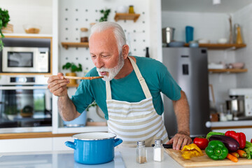 Happy retired senior man cooking in kitchen. Retirement, hobby people concept. Portrait of smiling...