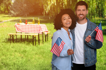 4th of July - Independence day of America. Happy couple with national flags of United States having picnic in park