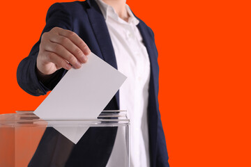 Woman putting her vote into ballot box on dark orange background, closeup