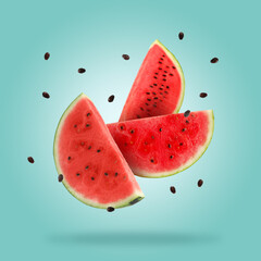 Slices of fresh juicy watermelon falling on light blue background