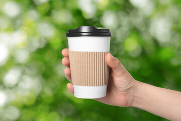 To-go drink. Woman holding paper cup of coffee on blurred green background, closeup