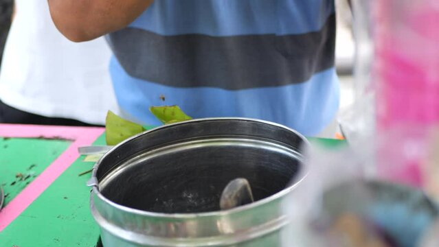 Es Puter Solo Seller serving customer. Traditional Javanese coconut ice cream sundae, with toppings of pandan noodle jelly and jackfruit.