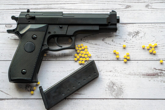 airsoft handgun with yellow bb, on white wooden background
