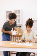 man and woman couple pay electricity rent bills drink tea. African American young married person in kitchen count expenses calculator. payment of utilities taxes, financial obligations mortgage loan