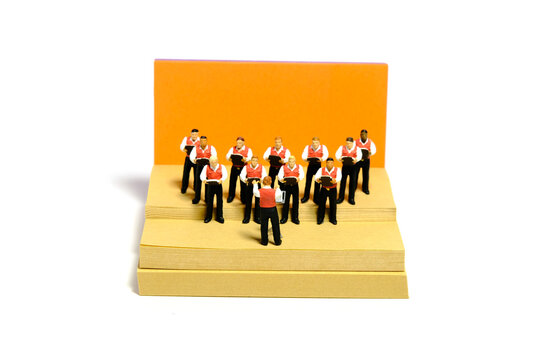 Creative miniature people toy figure photography. Sticky notes installation. Boys student doing choir performance on stage. Isolated on white background