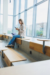 Pregnant woman sitting with laptop, smartphone, looking at laptop and taking notes while sitting in cafe. A woman works remotely on a laptop while on maternity leave