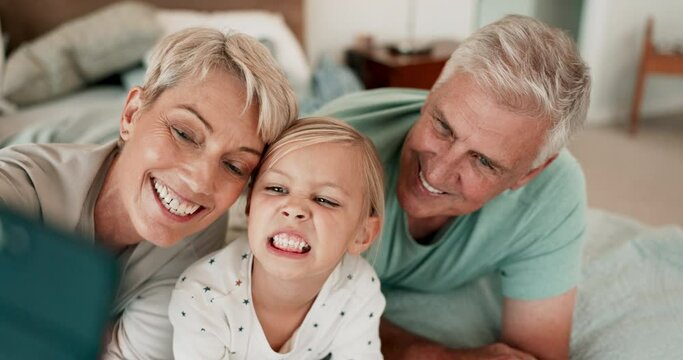 Funny face, selfie and a girl with grandparents on a bed in the home for a picture together or bonding. Love, kids or family photograph with happy senior man and woman with their granddaughter