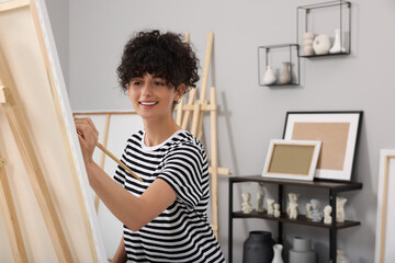 Young woman painting on easel with canvas in studio