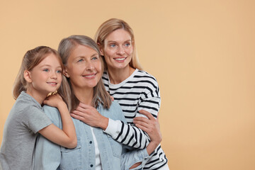 Three generations. Happy grandmother, her daughter and granddaughter on beige background, space for text