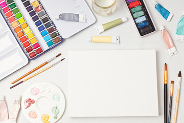 Artist painting color palettes, brushes and white canvas mockup. Craft hobby background. Recomforting, destressing hobby, art therapy