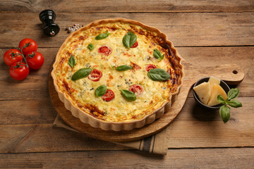 Delicious quiche with cheese, tomatoes and basil on wooden table