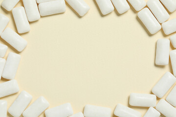 Frame made of tasty white chewing gums on beige background, flat lay. Space for text
