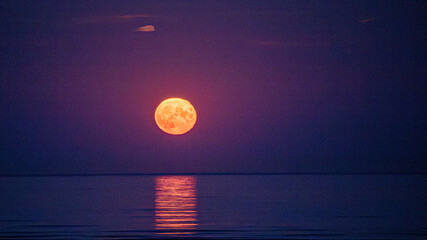 Obraz premium Super moon full moon rising above Irish Sea with reflection