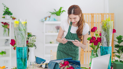 Young asian women owner floral store using smartphone take a photo bouquet sending to client. Women florist take a photo posing on social media or store online. Business and technology